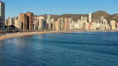 Yüksek binaları, güzel bir plajı ve görkemli uzak dağları olan bir kıyı şehrinin nefes kesici panoramik manzarası.