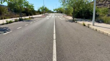 Bereketli yeşilliğin ortasında sakin bir yol, kentsel bozulma ile çarpıcı geri kazanım arasındaki zıtlığı gözler önüne seriyor.