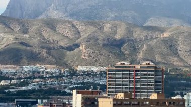 Canlı bir şehir alanına bakan nefes kesici dağ manzarası, doğayı ve şehir yaşamını benzer bir şekilde yakalıyor..