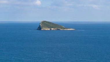 Göz kamaştırıcı ve güzel bir ada berrak gökyüzünün altındaki sakin ve dingin mavi sulardan zarifçe yükseliyor.