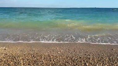 Huzurlu ve sakin bir sahil sahnesi. Nazik dalgalar, cennetin kumlu sahillerinde usulca süzülüyor.