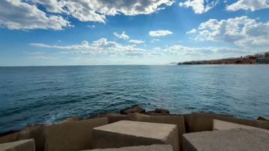 Çarpıcı bir kıyı manzarası dramatik bulut oluşumlarının yanında sakin suların güzel bir resmini çiziyor.