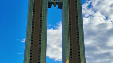 Güzel bir gökyüzüne karşı kendine özgü mimari tasarımı olan modern bir kulenin çarpıcı bir görüntüsü..