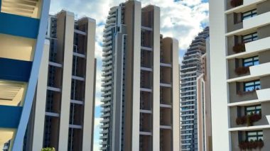Dinamik bulut oluşumlarıyla dolu canlı bir gökyüzüne güzel bir şekilde yerleştirilmiş çarpıcı modern binalar keşfedin.