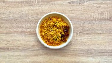 Lezzetli bir yemek için mükemmel baharatlar, fasulyeler ve tuzlu parçalar içeren canlı bir kase sarı pirinç..