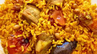 Canlı bir tabak Jollof pilavı, et ve taze sebzelerle süslenmiş, özel durumlar için mükemmel.