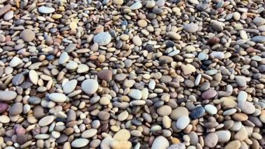 Berrak mavi suları ve kıyıya vuran nazik dalgaları olan harika bir çakıl taşı sahili manzarası.