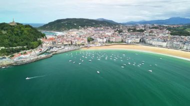 Çarpıcı bir sahil şehrinin havadan görünüşü. Canlı bir plajı ve manzaraya dağılmış tekneleri var.