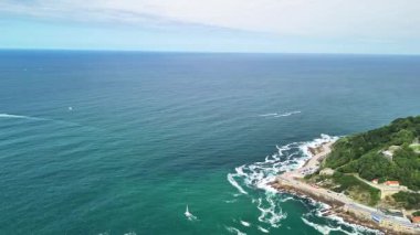 Bu nefes kesici hava manzarası büyüleyici bir kıyı şeridi, bir ada ve canlı bir şehir manzarası sergiliyor.