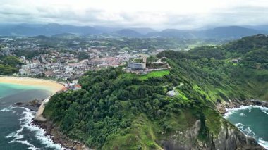 Yakındaki bir sahil ve şehrin yanındaki yemyeşil bir sahil tepesini güzel gösteren nefes kesici bir hava görüntüsü.