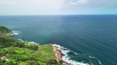 Resimli sahil şeridi boyunca kayalıkların ve canlı yeşilliklerin nefes kesici hava manzarası
