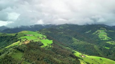 Nefes kesici bir manzara, geniş bulutlu gökyüzü altında yemyeşil tepeler sergiliyor, doğa severler için ideal.