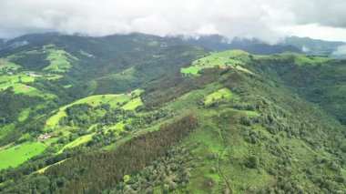 Bu nefes kesici hava manzarası güzel bir şekilde sergileniyor yemyeşil tepeler ve bulutlu gökyüzünün altındaki dingin vadiler.