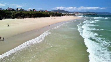 Muhteşem bir kumsal sahnesi, yuvarlanan dalgalar, ve sonsuz mavi gökyüzü, mükemmel bir gün yaratıyor.