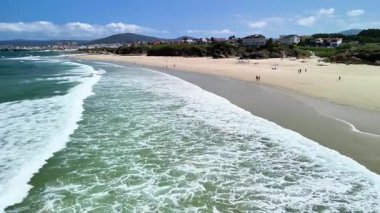 Nefes kesen bir sahil manzarası hafif dalgaları ortaya çıkarır ve açık mavi bir gökyüzü, tam bir rahatlama için idealdir.