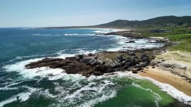 Bu çarpıcı plaj sahnesi kayalık kıyıları, yemyeşil suları ve okyanus dalgalarının rahatlatıcı sesini sergiliyor.