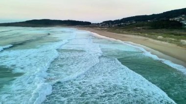 Kesinlikle nefes kesici bir hava manzarası alacakaranlıkta sakin bir plajda sallanan yumuşak dalgaları yakalar.