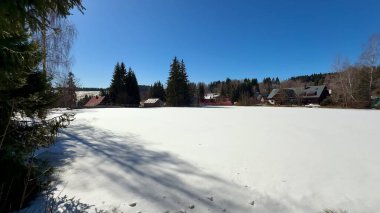 Çok güzel, sakin bir kış manzarası. Engin, karla kaplı bir tarlayı gözler önüne seriyor. Parlak, mavi bir gökyüzünün altında.