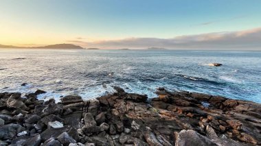 Gün batımında okyanus dalgalarının güçlü bir şekilde kayalık kıyılara çarptığını görmek.