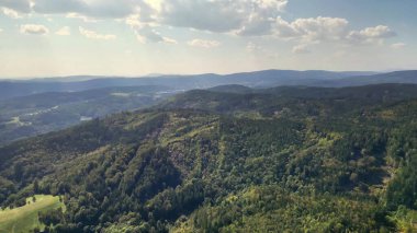 Yeşil dağların ve yuvarlanan tepelerin çarpıcı hava perspektifi, doğanın sükunetini yakalıyor..