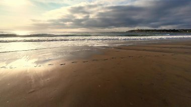 Yumuşak dalgaların ve kumdaki ayak seslerinin yer aldığı sakin bir sahil sahnesi, rahatlama temaları için mükemmel..