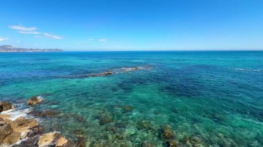 Engebeli ve görkemli uçurumların yanında berrak suları gösteren nefes kesici kıyı manzarası.