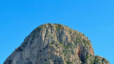 Nefes kesen kayalık bir tepe görkemli bir şekilde canlı mavi gökyüzüne karşı duran doğal güzelliği sergiliyor.