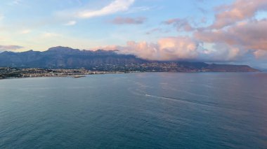 Güneşin doğuşunda şaşırtıcı derecede güzel bir kıyı manzarası muhteşem dağları ve sakin suları gözler önüne seriyor.