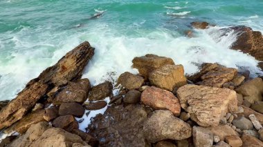 Engebeli kıyılara çarpan güçlü okyanus dalgalarının çarpıcı görüntüsü, doğanın ihtişamını yakalıyor.