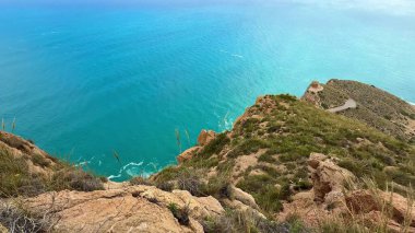 Kayalık bir uçurumdan gelen turkuaz denizin çarpıcı manzarası nefes kesici güzelliği ve cazibesini sergiliyor.