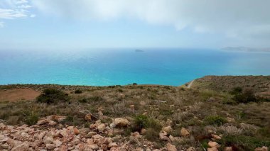 Çarpıcı turkuaz sulara ve kayalık araziye bakan manzaralı bir tepeden nefes kesici bir manzaranın tadını çıkarın.