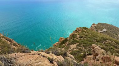 Canlı yemyeşil bir yeşil ile çevrili kayalık bir uçurumdan turkuaz suların nefes kesici manzarasının tadını çıkar.