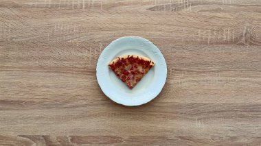 Lezzetli, ağız sulandıran bir dilim pizza zarif bir tabakta sunuluyor, tutkulu yemek severler için ideal.