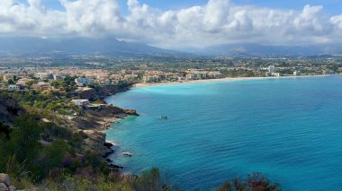 Güzel turkuaz suların ve yemyeşil yeşilliklerin yer aldığı sakin bir sahil şeridinin nefes kesici hava manzarası.