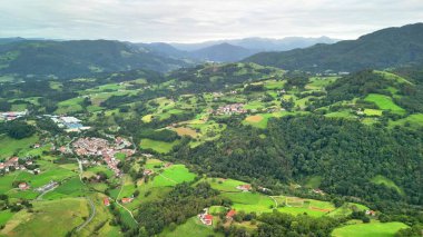 Arkasında görkemli dağlar olan canlı yeşil manzaraların çarpıcı hava aracı görüntüleri.