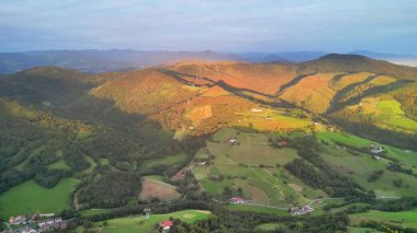 Nefes kesen hava manzarası. Yuvarlanan tepeler ve gün batımında aydınlatılan canlı yeşil alanlar..
