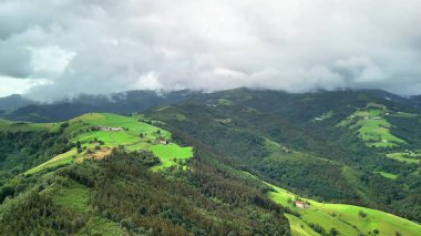 Nefes kesici bir manzara, geniş bulutlu gökyüzü altında yemyeşil tepeler sergiliyor, doğa severler için ideal.