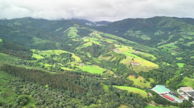 Bulutlu gökyüzünün altındaki yemyeşil tepelerin ve vadilerin büyüleyici görüntüleri doğanın güzelliğini gözler önüne seriyor..