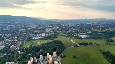 Bu çarpıcı hava manzarası geniş yemyeşil tarlalar ve tepelerin arasına kurulmuş şehir binalarını güzel bir şekilde sergiliyor.