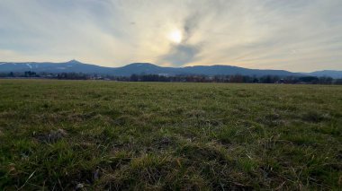 Heybetli dağların, açık otlakların ve sakin bir alacakaranlık gökyüzünün yer aldığı şaşırtıcı derecede huzurlu bir manzara.