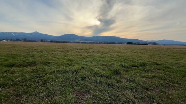 Muhteşem dağlarla dolu engin ve açık bir arazinin nefes kesici ve çarpıcı manzarası güzel bir günbatımı gökyüzünün altında.