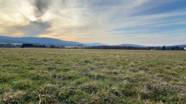 Nefes kesen sakin bir manzara geniş açık araziler ve bulutlu bir gökyüzünün altındaki güzel resimli tepeler.