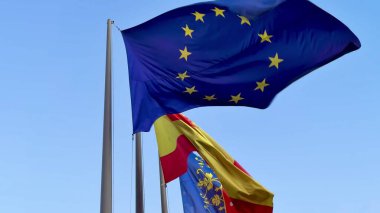 Avrupa Birliği ve İspanya 'nın bayrakları açık mavi bir zemin üzerinde gururla el sallıyor.
