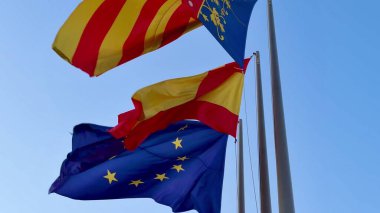 İspanya, Katalonya ve AB 'yi temsil eden renkli ve canlı bayraklar yumuşak meltemde zarifçe dalgalanıyor