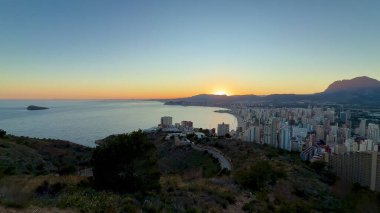 Nefes kesen gün doğumunun nefes kesici manzarası kıyı şehri ve görkemli dağların üzerine altın renkler döküyor.