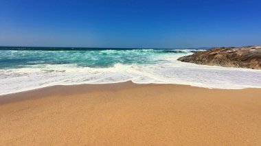 Sakin, berrak mavi bir gökyüzünün altında dalgaların yanında altın kumu aydınlatan nefes kesici bir sahneydi.