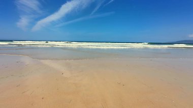 Huzurlu bir sahil manzarası yumuşak, altın kumlar ve nazikçe dalgalanan okyanus dalgaları, nihai rahatlama için mükemmel