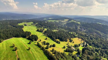 Parlak, geniş bir gökyüzü altında canlı tarlaları ve dingin tepeleri olan çarpıcı bir manzaranın havadan görüntüsü.