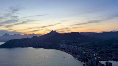 Büyüleyici bir hava manzarası güzel bir gün batımında canlı bir sahil şehrinin muhteşem bir gösterisini sunuyor.