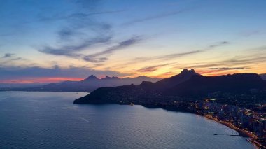 Güzel sahil şehrinin üzerinde nefes kesici bir günbatımı görkemli dağları ve ışıldayan suları aydınlatıyor.